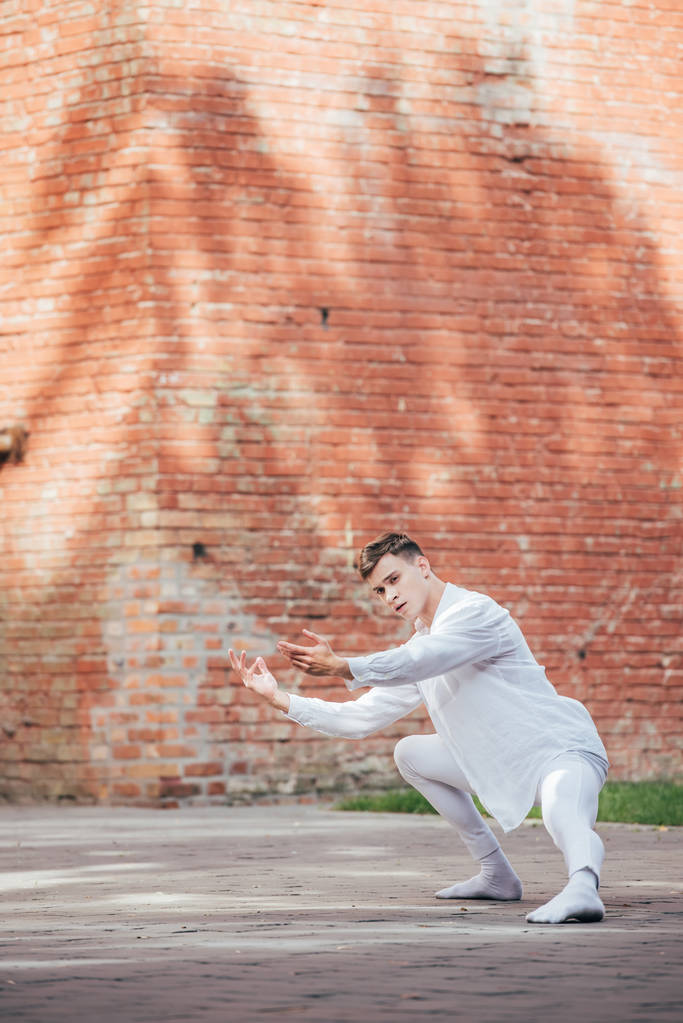 bonito jovem masculino bailarino balé em branco roupas dançando no urbano rua
    - Foto, Imagem