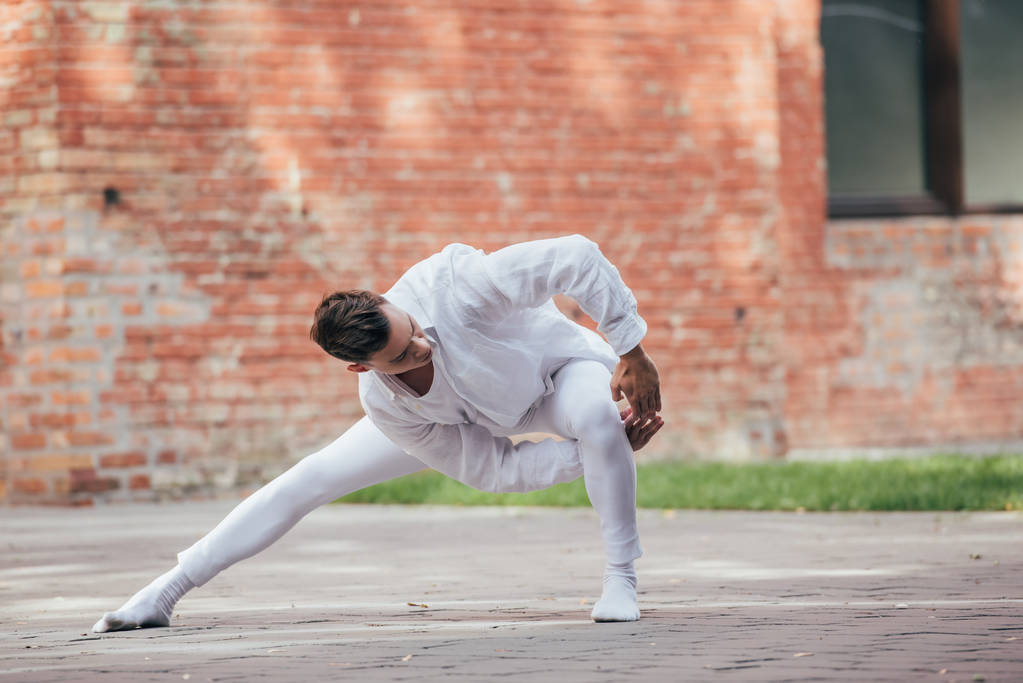 beau jeune danseur masculin en vêtements blancs dansant dans la rue urbaine
    - Photo, image