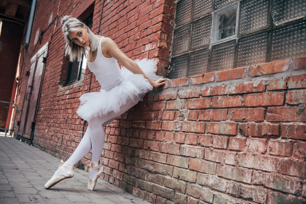 krásná mladá baletka se na cihlovou zeď a koukal - Fotografie, Obrázek