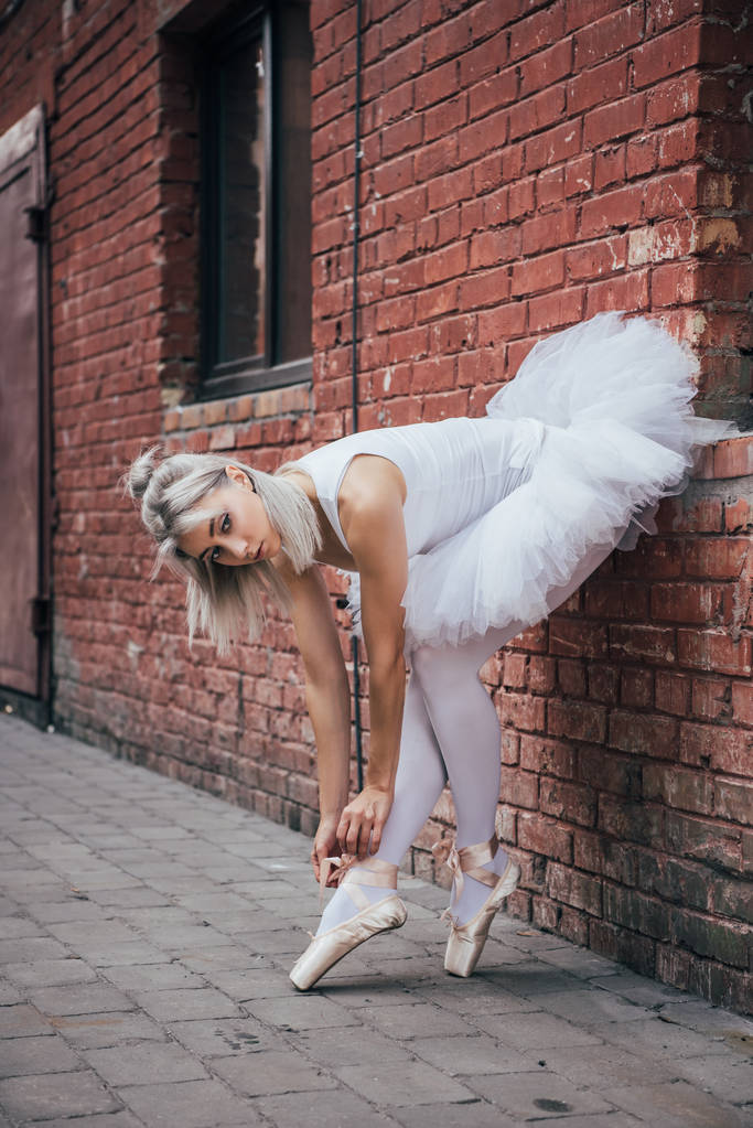 attraente giovane ballerina appoggiata al muro di mattoni e legatura scarpa da punta
 - Foto, immagini