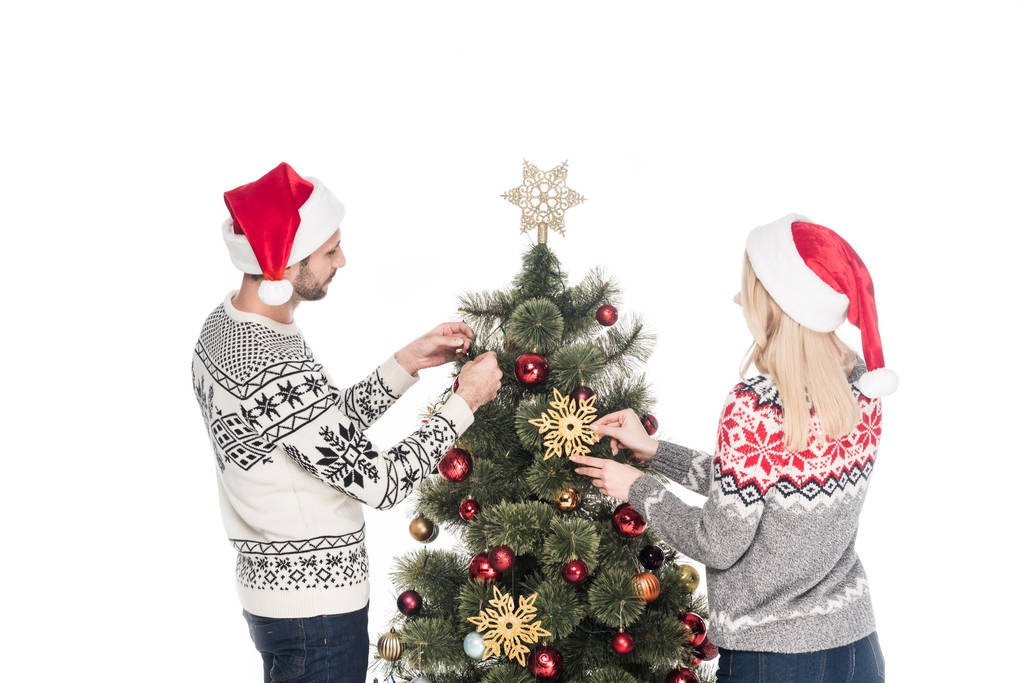 назад вид подруги и бойфренда в свитерах, украшающих рождественскую елку вместе изолированные на белом
 - Фото, изображение