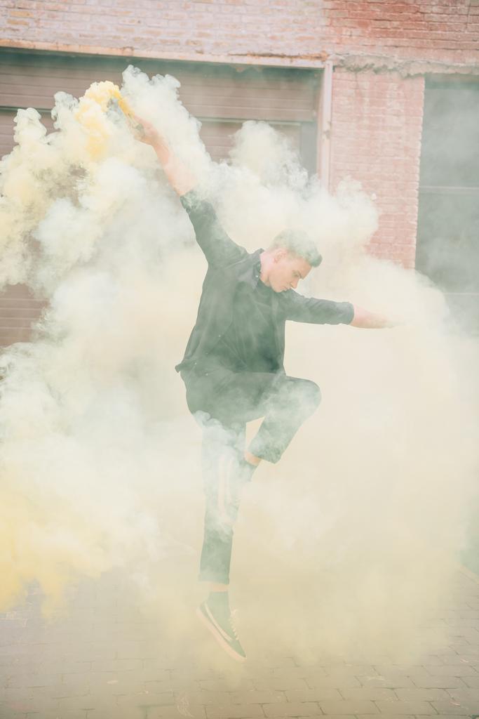 молодий чоловік сучасний танцюрист стрибає в диму на міській вулиці
 - Фото, зображення