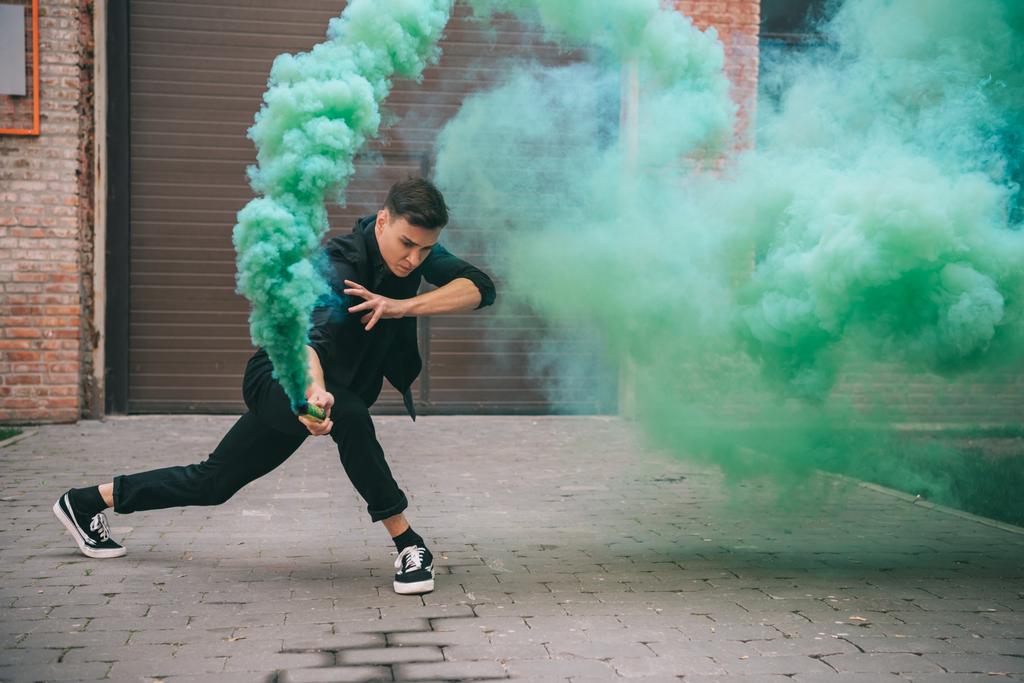 νεαρός άνδρας που χορεύει στο πράσινο αιθάλης στον αστικό δρόμο της πόλης  - Φωτογραφία, εικόνα