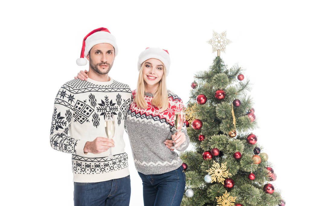 coppia sorridente innamorata in cappelli Babbo Natale con bicchieri di champagne all'albero di Natale isolato su bianco
 - Foto, immagini