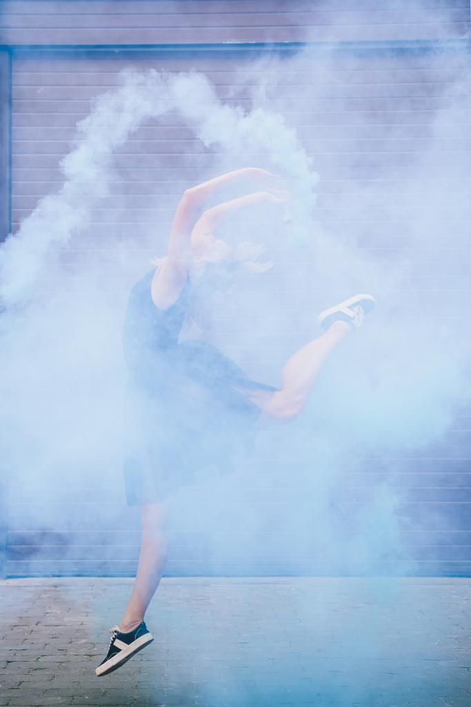 θηλυκό νεαρή χορεύτρια σύγχρονου χορού χορό στην γαλάζιος καπνός που βγαίνει στην οδό  - Φωτογραφία, εικόνα