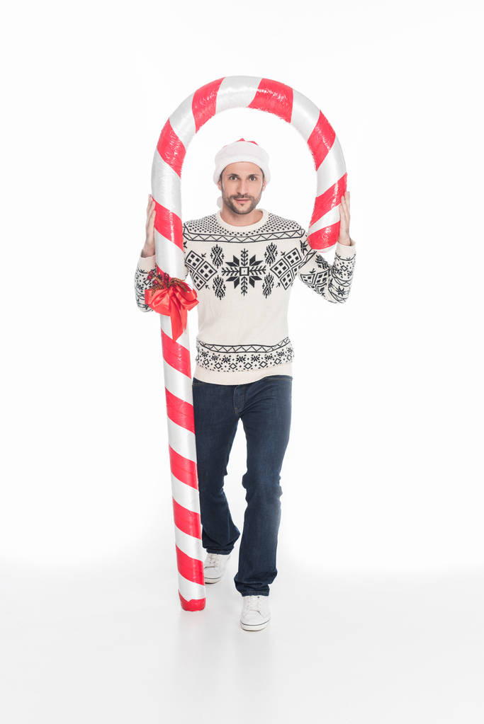 fiatal férfi pulóver és a santa claus kalap játék candy elszigetelt fehér - Fotó, kép
