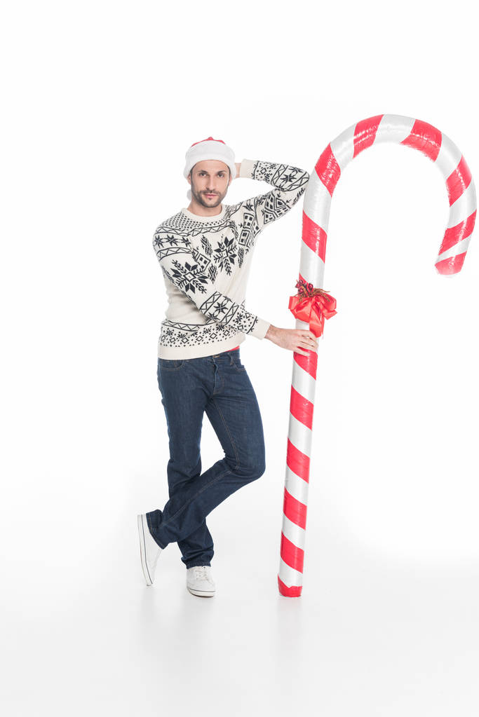 白で隔離おもちゃキャンデーとセーターを着て、サンタ クロースの帽子の若い男 - 写真・画像
