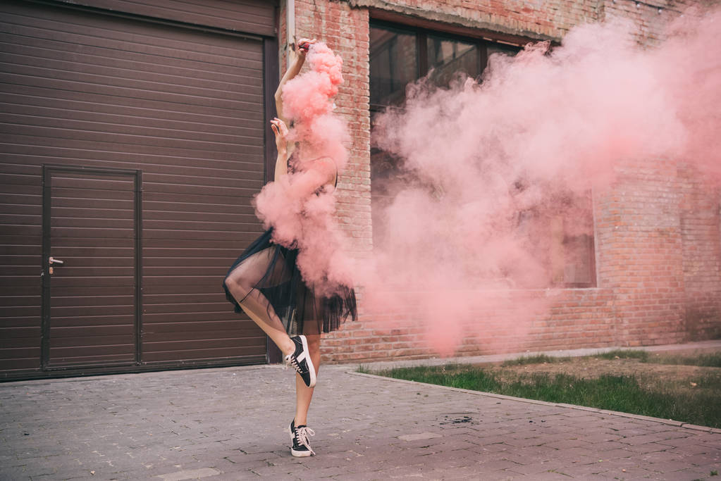 νεαρή γυναίκα σύγχρονη χορεύτρια σε ροζ καπνό στον δρόμο - Φωτογραφία, εικόνα