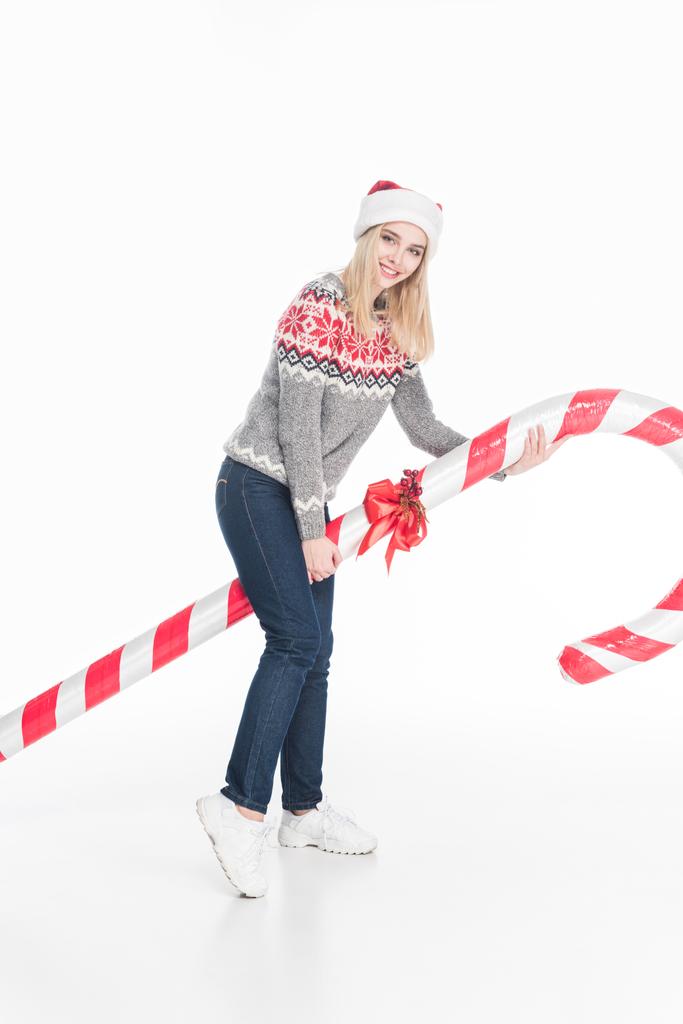 jonge vrouw in de trui en kerstman hoed bedrijf speelgoed snoep geïsoleerd op wit - Foto, afbeelding