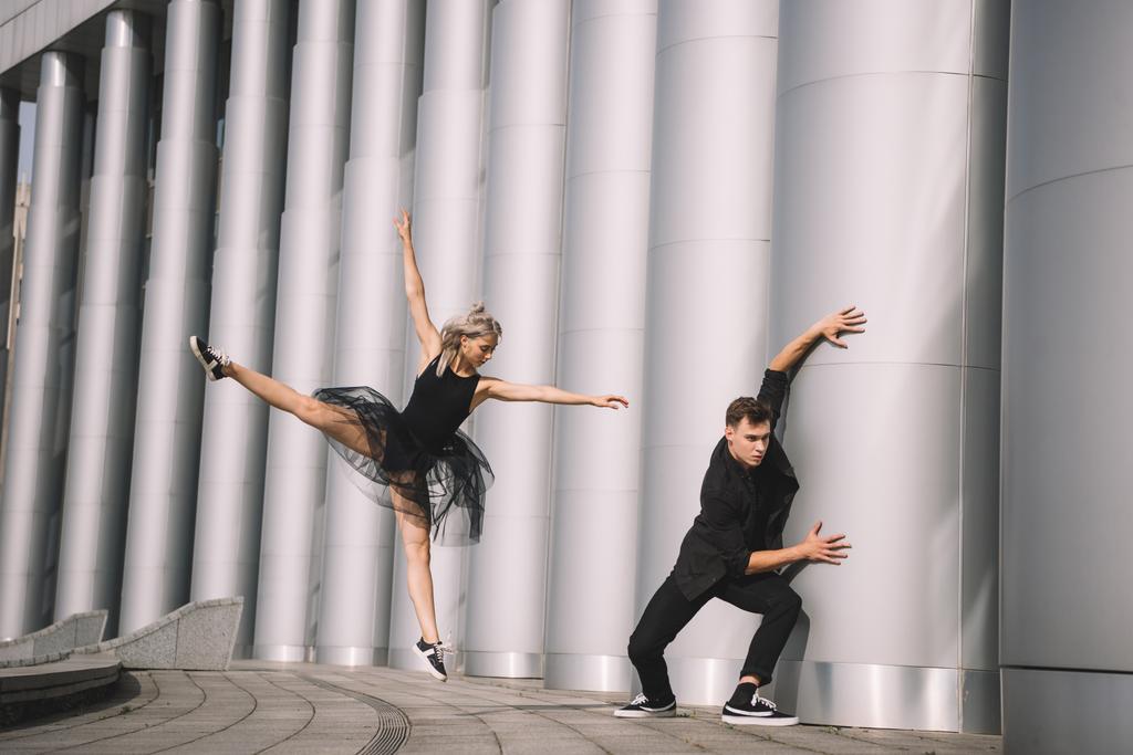 όμορφη νεαρή χορευτές σε μαύρα ρούχα χορό κοντά σε στήλες     - Φωτογραφία, εικόνα