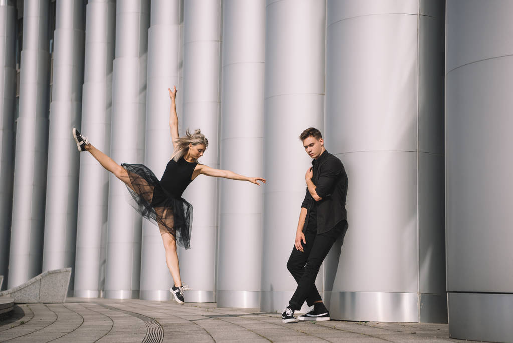 νεαρό ζευγάρι χορευτών σε μαύρα ρούχα χορό κοντά σε στήλες    - Φωτογραφία, εικόνα