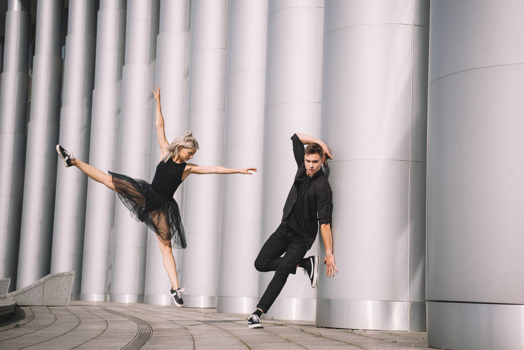 hermosa pareja joven de bailarines en ropa negra bailando cerca de columnas
    - Foto, imagen
