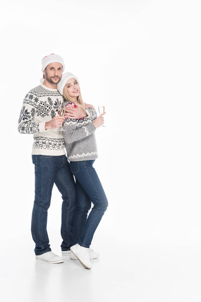 νεαρό ζευγάρι στο πουλόβερ με ποτήρια σαμπάνιας που απομονώνονται σε λευκό - Φωτογραφία, εικόνα