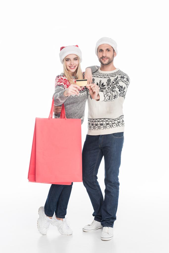 ζευγάρι στο Βασίλη καπέλα, τσάντες αγορών με πιστωτική κάρτα που απομονώνονται σε λευκό - Φωτογραφία, εικόνα