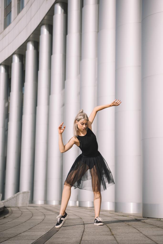 beautiful young woman in black skirt dancing near columns - Photo, Image