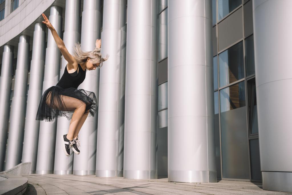 bajo ángulo vista de hermosa bailarina joven saltando y bailando en la calle
  - Foto, Imagen