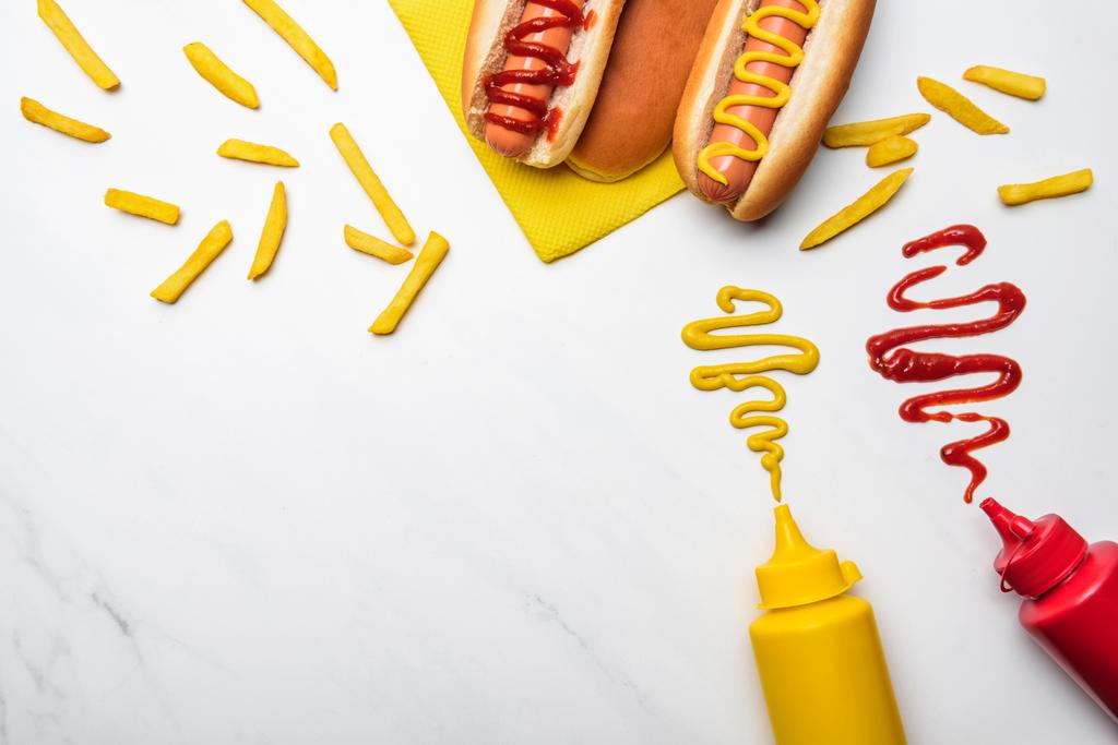 hotdogs met mosterd en ketchup op witte marmeren oppervlak (bovenaanzicht) - Foto, afbeelding