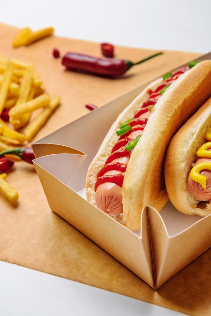 gros plan de hot-dogs dans un plateau en carton avec des frites sur du papier parchemin
 - Photo, image