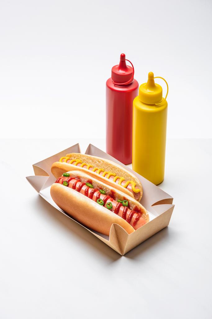 zbliżenie pikantny hot dogi z musztardą i ketchupem na biały - Zdjęcie, obraz