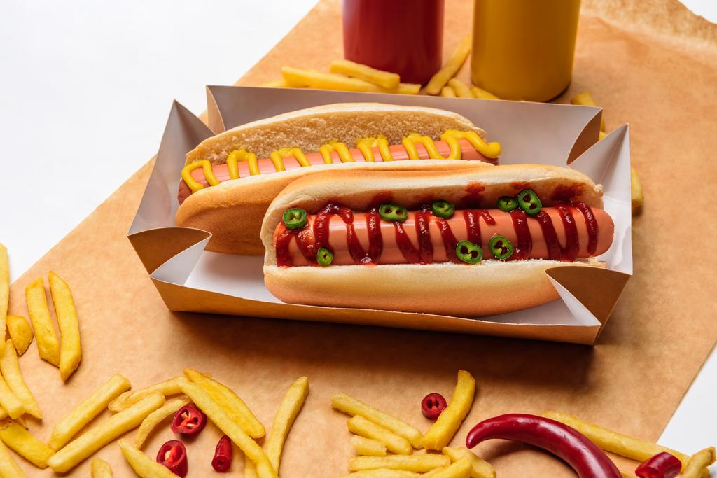 zbliżenie o hot-dogi z frytkami na papierze na białej powierzchni - Zdjęcie, obraz
