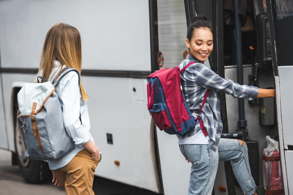 Junge multiethnische Reisende mit Rucksäcken gehen auf der Straße in Reisebus - Foto, Bild