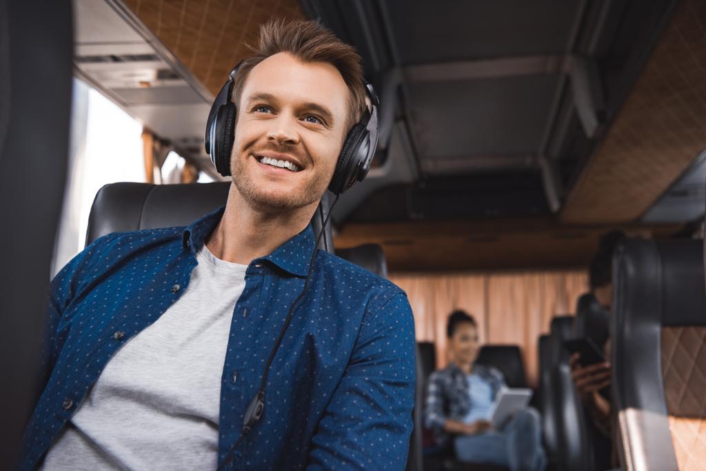 veselý muž ve sluchátkách poslouchat hudbu během cesty v autobuse cestovní  - Fotografie, Obrázek