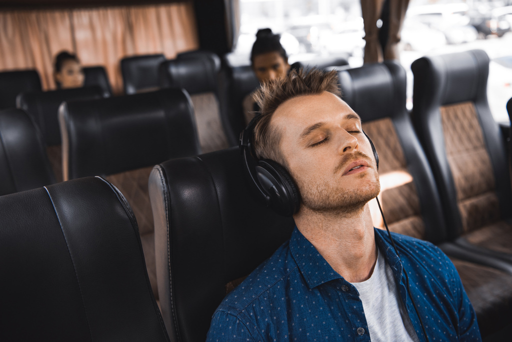 dorosły człowiek w słuchawkach, słuchania muzyki i spanie podczas podróży na autobus  - Zdjęcie, obraz
