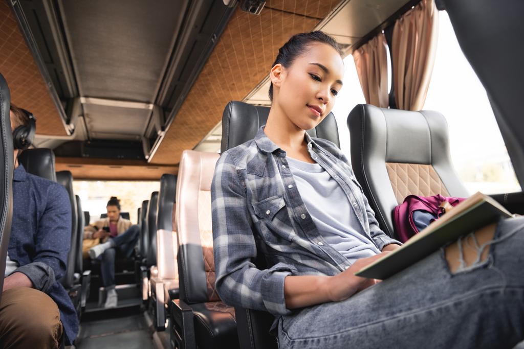 alacsony, szög, kilátás az ázsiai női utas olvasókönyv út során utazik a buszon  - Fotó, kép