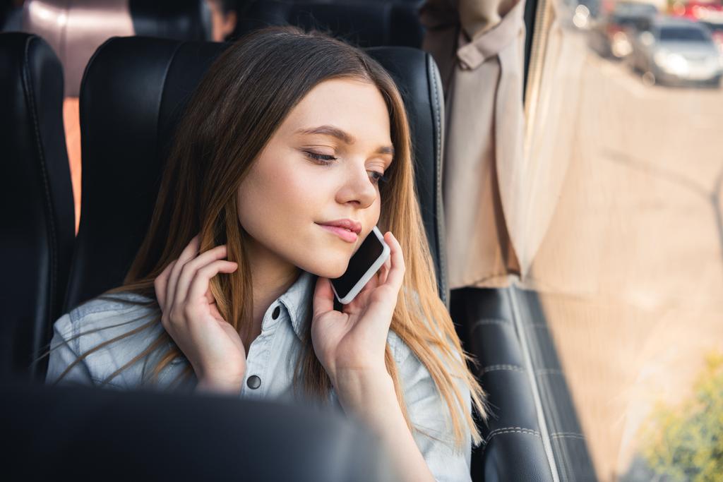 hermosa mujer joven hablando en el teléfono inteligente durante el viaje en autobús
  - Foto, imagen