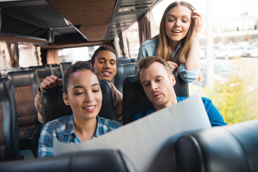 νεαρών τουριστών ευτυχισμένη κοιτάζοντας το χάρτη κατά τη διάρκεια ταξιδιού σε λεωφορείο ταξιδιωτικό - Φωτογραφία, εικόνα