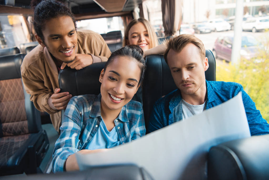 souriant amis multiculturels regardant la carte pendant le voyage en bus
 - Photo, image