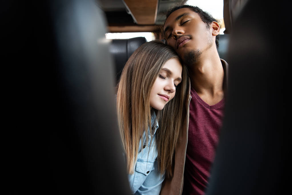 selective focus of young interracial couple sleeping during trip on travel bus - Photo, Image