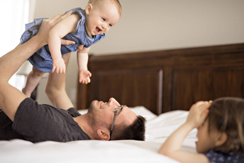 Ojciec, grając ze swoim dzieckiem w sypialni - Zdjęcie, obraz