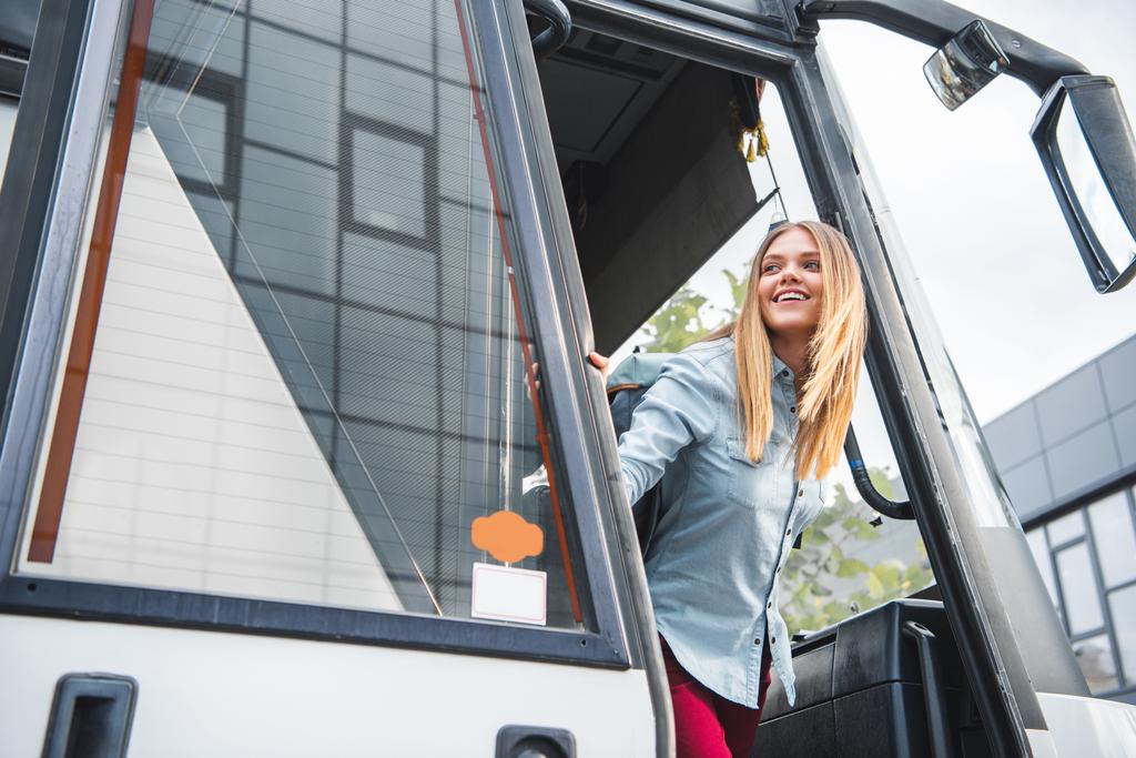 щаслива жінка-туристка з рюкзаком, що дивиться з автобуса на вулиці
 - Фото, зображення