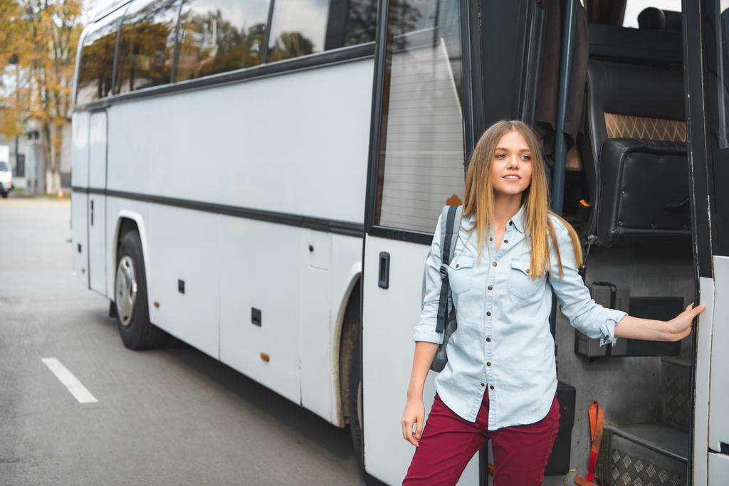 Młoda kobieta z plecak stojący w pobliżu podróży autobusem na ulicy - Zdjęcie, obraz