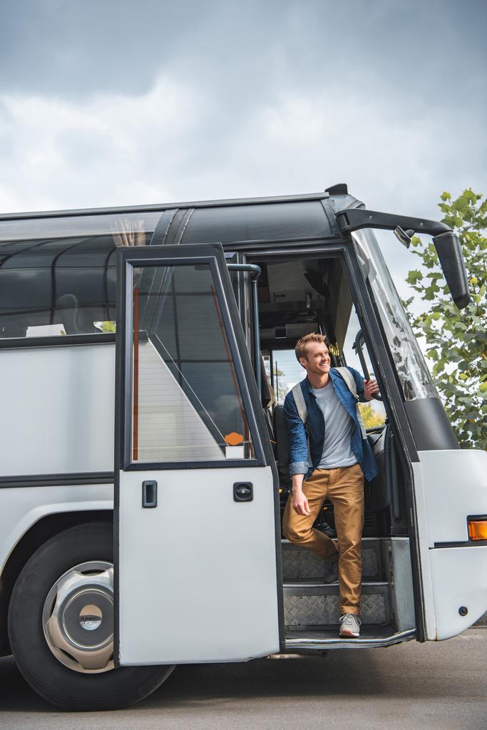 boldog férfi utas hátizsákkal kisétált a busz a város utca - Fotó, kép