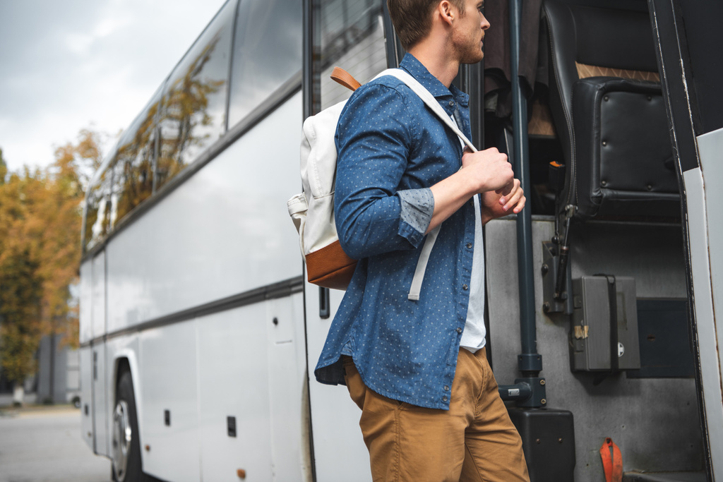 vista lateral del turista masculino con mochila caminando en autobús de viaje en la calle urbana
 - Foto, Imagen