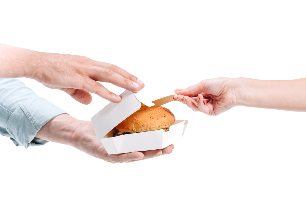περικομμένη εικόνα γυναίκα Άνοιγμα πακέτου με ανθυγιεινά burger που απομονώνονται σε λευκό - Φωτογραφία, εικόνα
