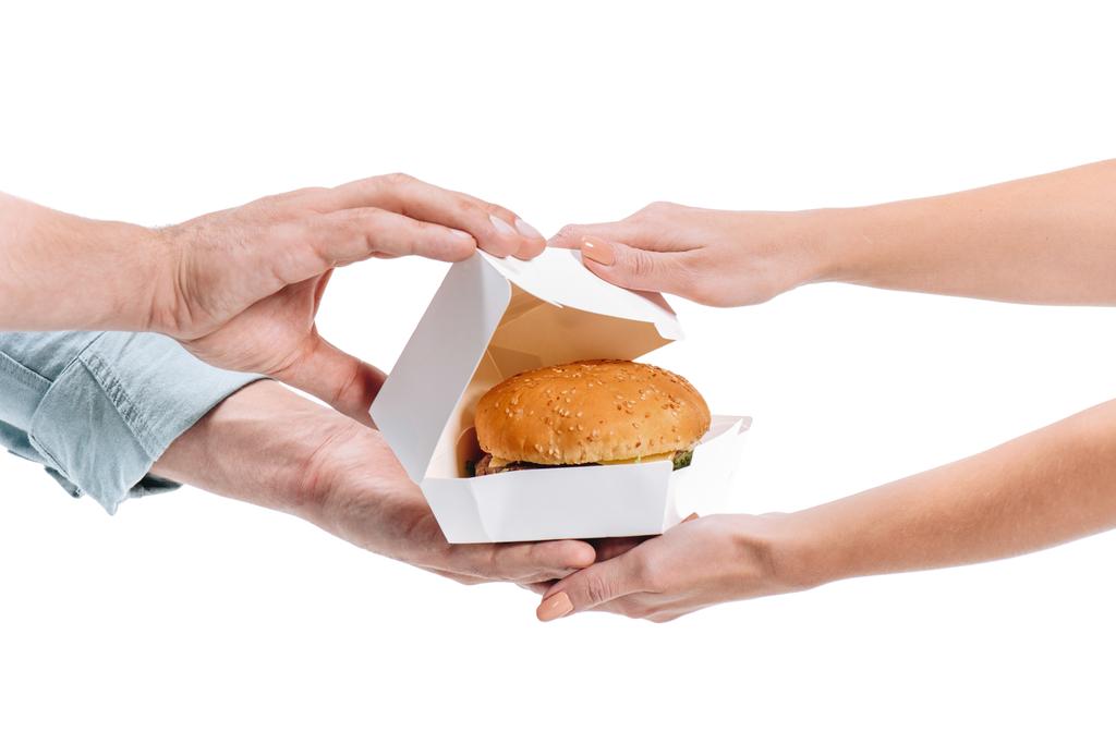bijgesneden afbeelding van de vrouw open pakket met ongezonde fast food geïsoleerd op wit - Foto, afbeelding