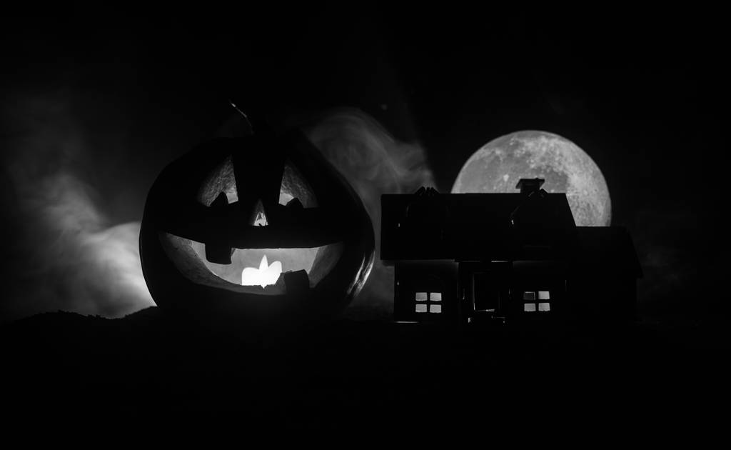 Vista dell'orrore della zucca di Halloween con la faccia sorridente spaventosa. Lanterna jack testa con edificio infestato e albero su sfondo scuro tonica nebbiosa
. - Foto, immagini