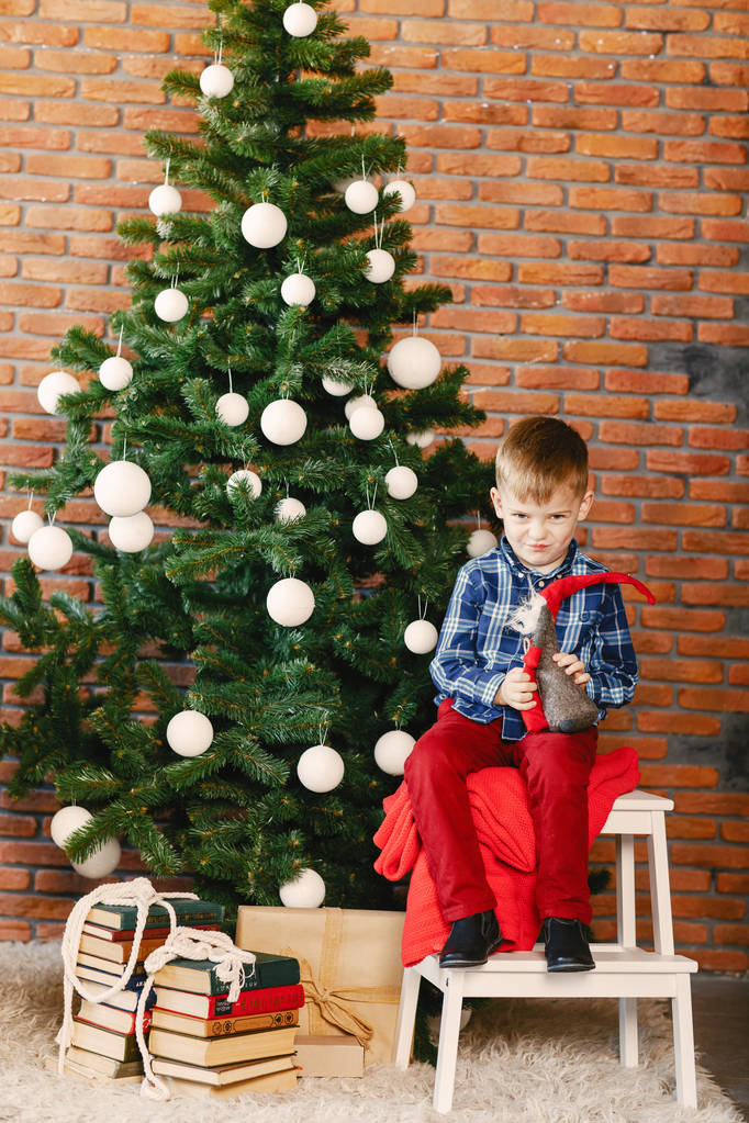 menino feliz jogando junto à árvore de natal
 - Foto, Imagem