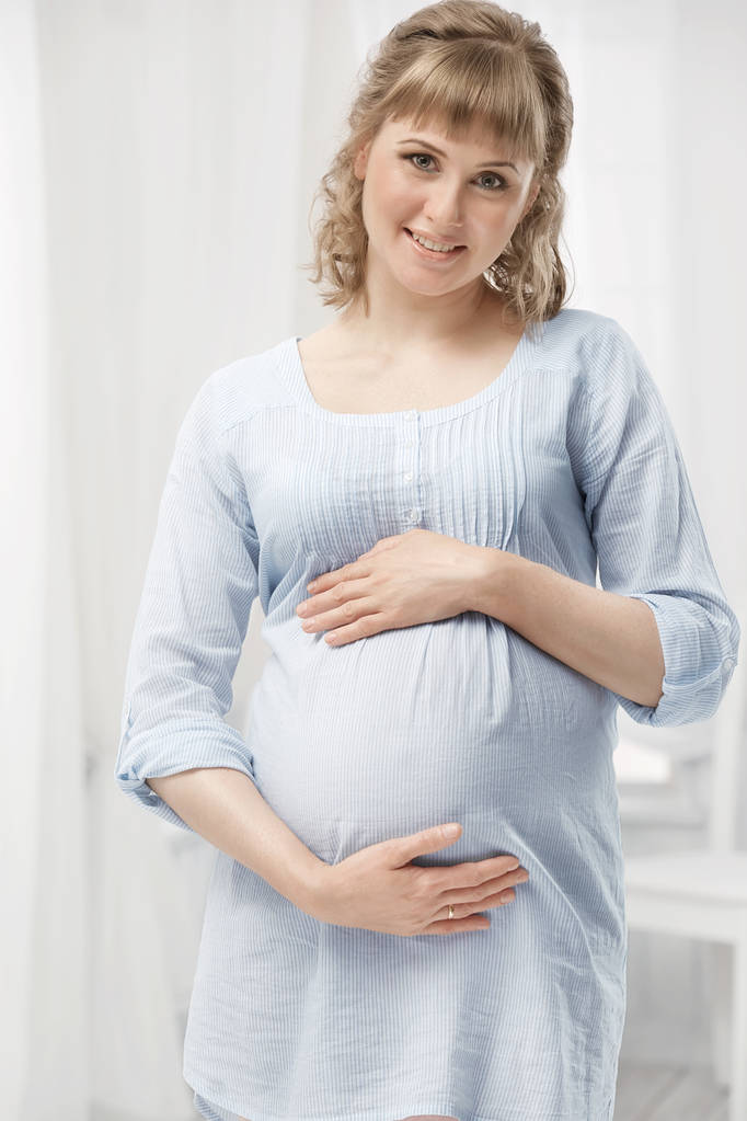 Портрет молодой беременной женщины в интерьере
 - Фото, изображение