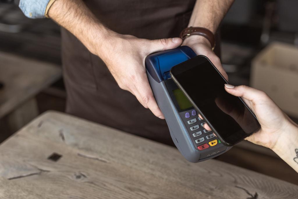 ödemeyi kafede smartphone ile temassız satın alma yaparken müşteri ise terminal içeren garson kadeh kırpılmış - Fotoğraf, Görsel