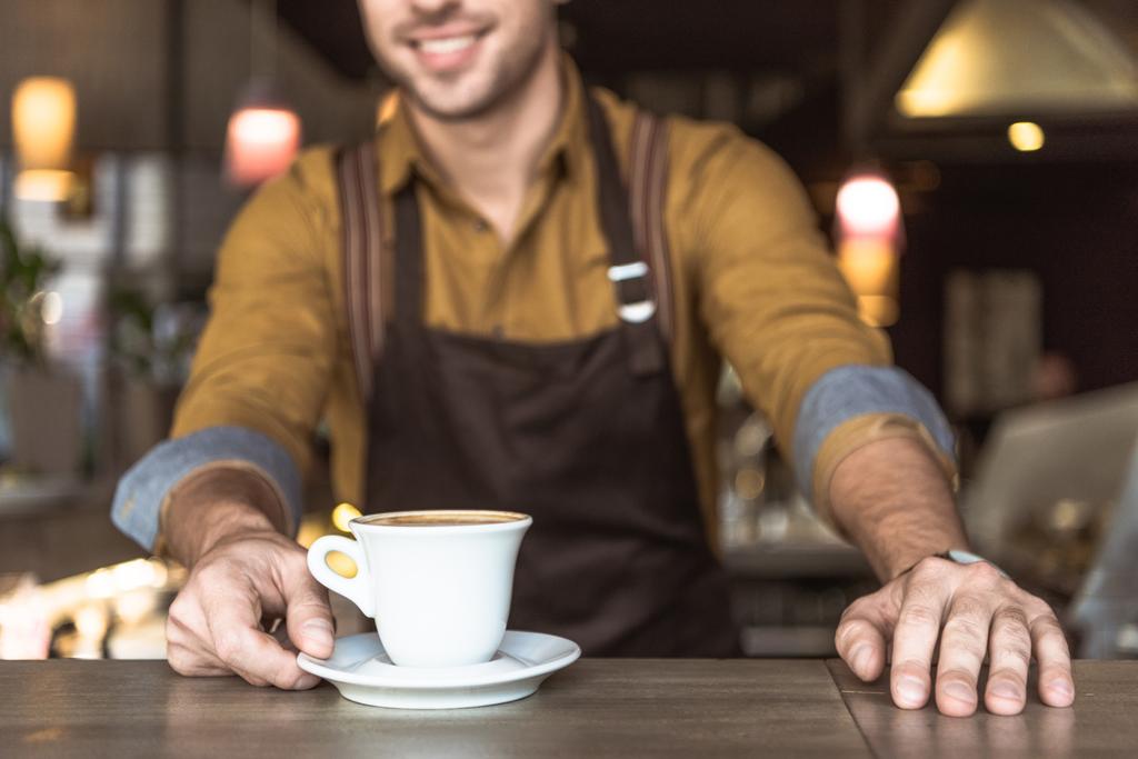 обрезанный кадр молодого баристы с чашкой вкусного кофе
 - Фото, изображение