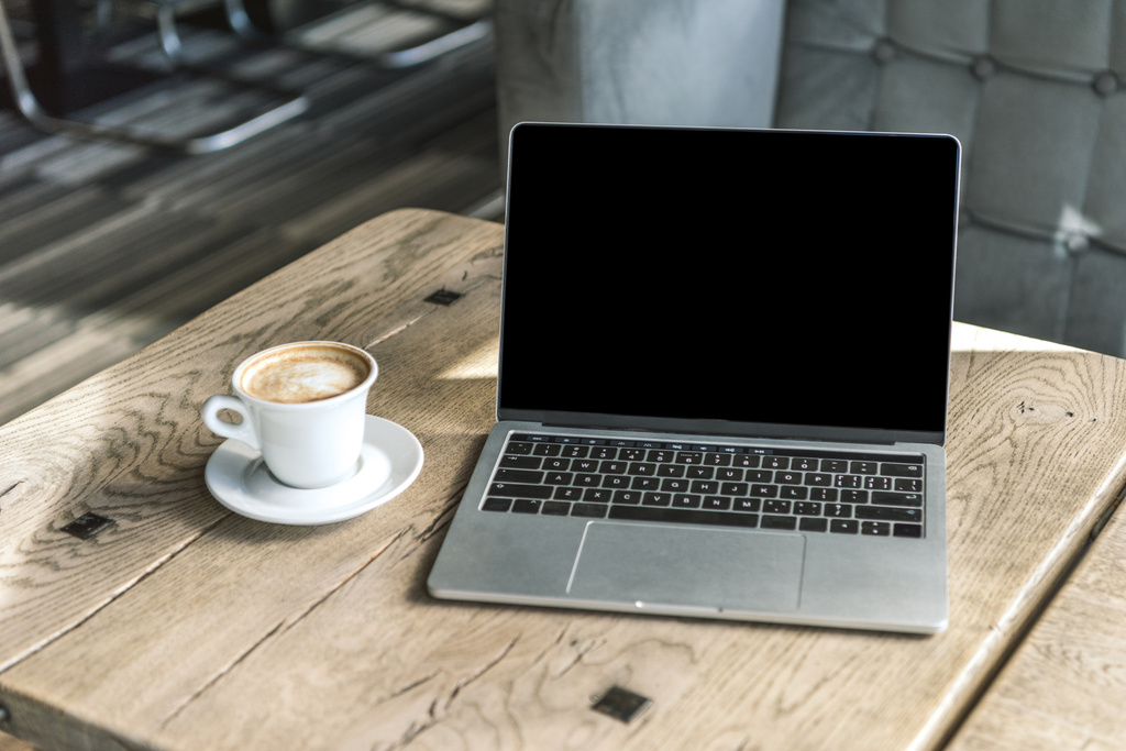 一杯のコーヒーとカフェで素朴な木製のテーブルで空白の画面を持つノート パソコン - 写真・画像