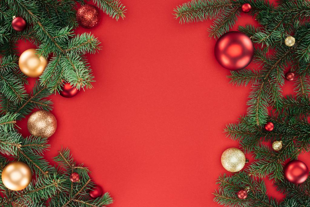 pose plate avec des branches de pin avec des boules de Noël rouges et dorées isolées sur rouge
 - Photo, image