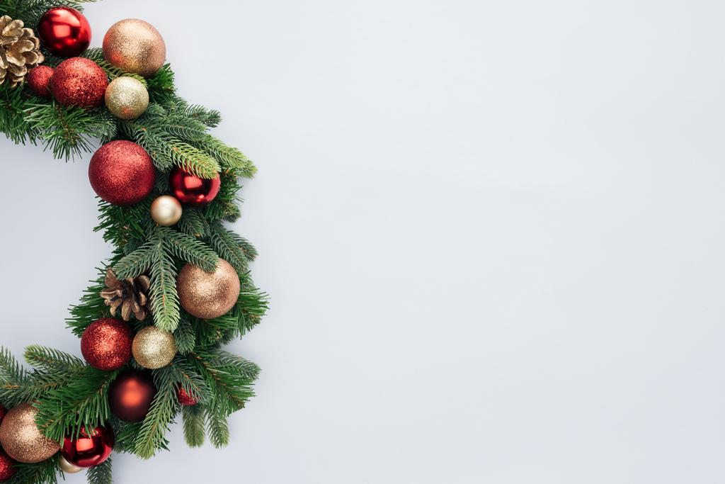Верхний вид декоративного праздничного венка с красными и золотыми рождественскими игрушками, изолированными на белом
 - Фото, изображение