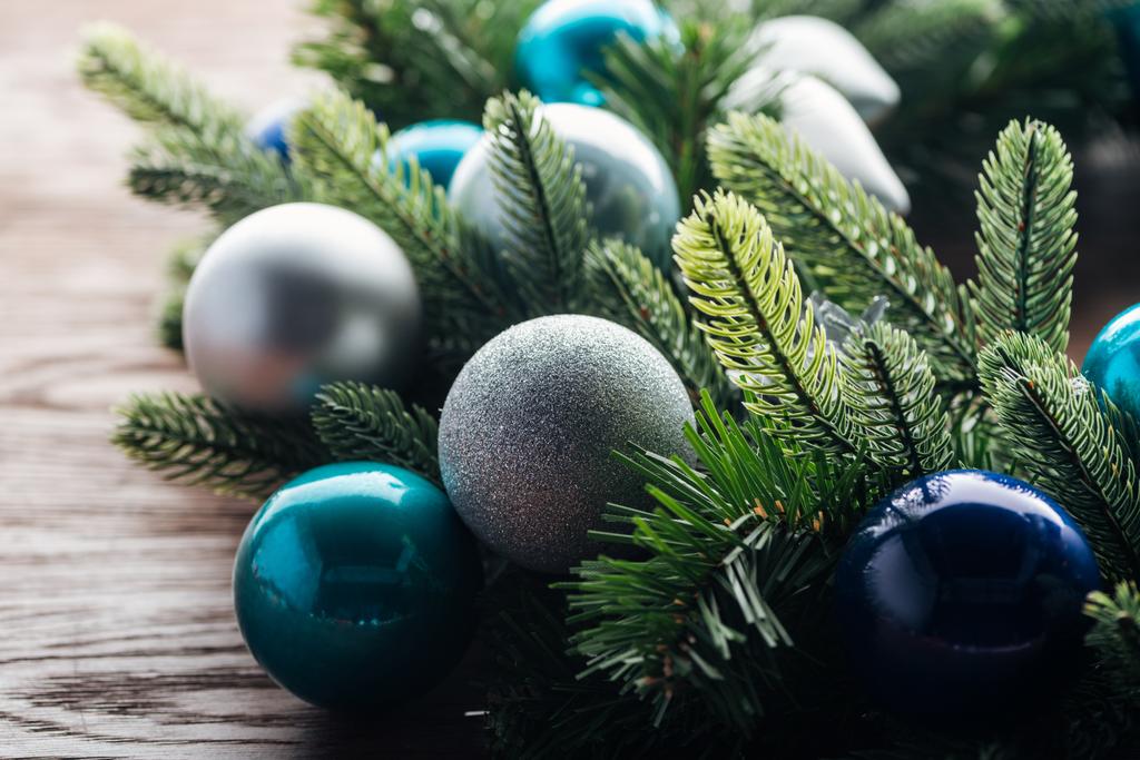 κλείνω πάνω θέα πεύκο δέντρο στεφάνι με μπλε και ασημένια Χριστούγεννα παιχνίδια σε φόντο ξύλινη - Φωτογραφία, εικόνα