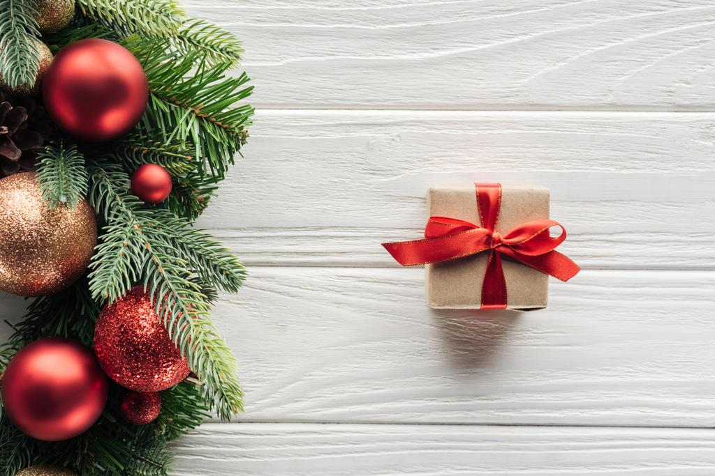 Kranz von oben mit Weihnachtsspielzeug und verpacktem Geschenk auf weißer Holzoberfläche - Foto, Bild
