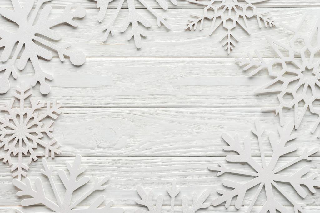tendido plano con copos de nieve decorativos sobre mesa de madera blanca con espacio en blanco en el centro
 - Foto, imagen